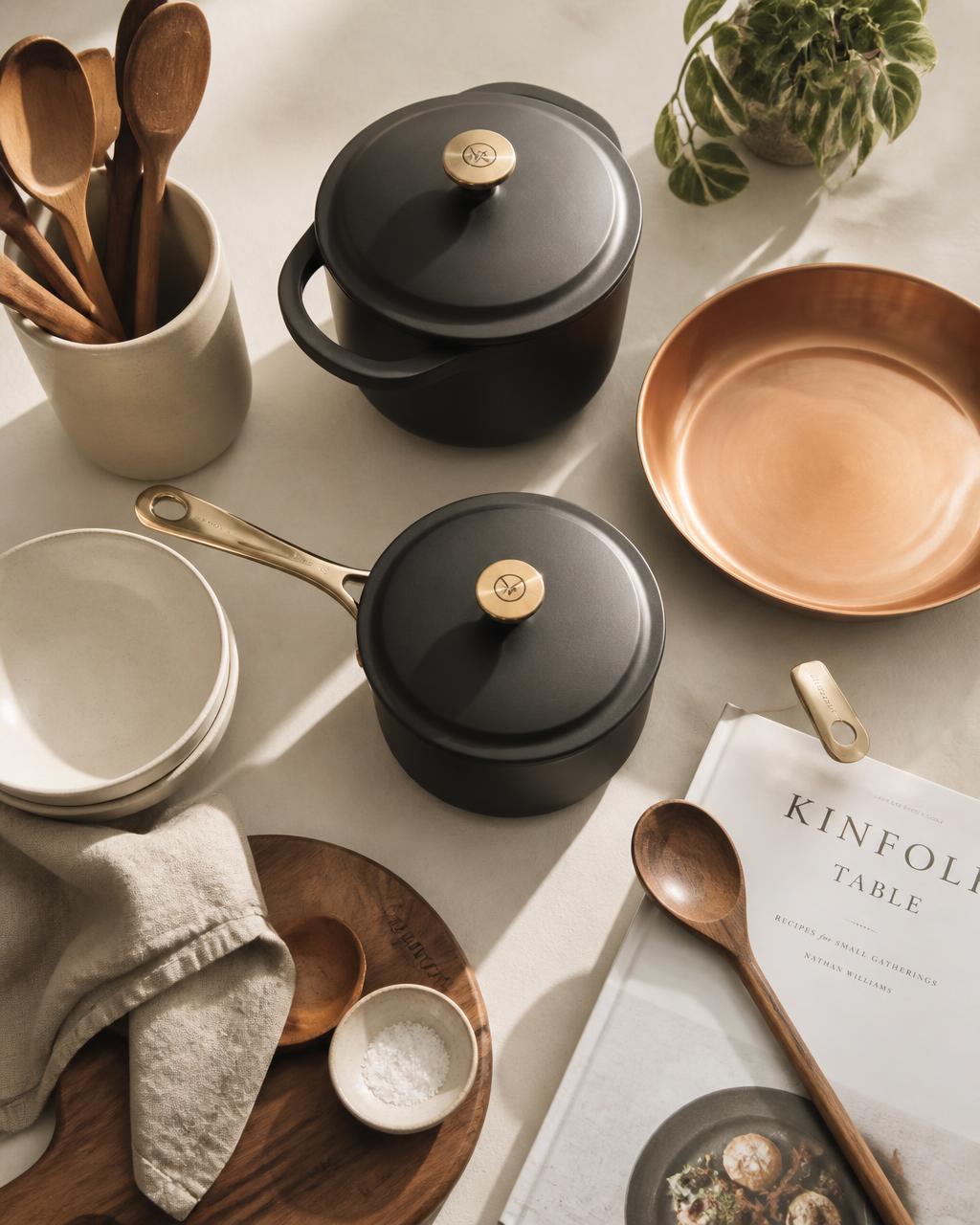 Charcoal cookware, wooden utensils and ceramics on a sunlit kitchen counter